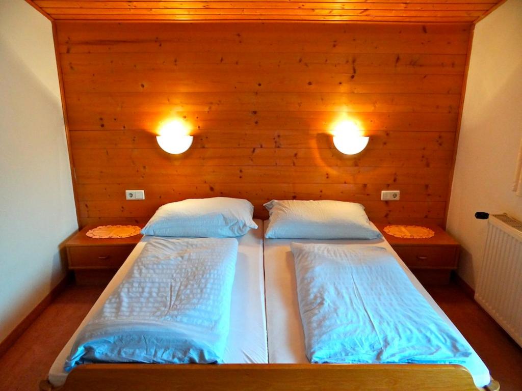 a bedroom with two beds and two lights on the wall at Ski & Bike Pension Maria in Saalbach Hinterglemm