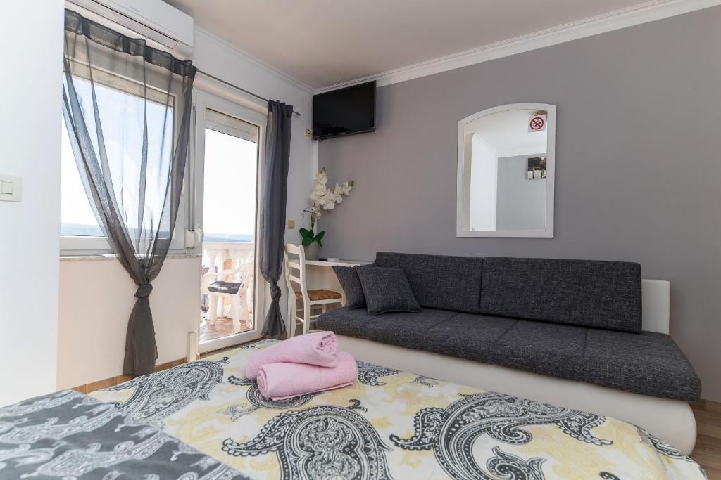 a bedroom with a bed and a couch and a window at Guest House Berto in Crikvenica