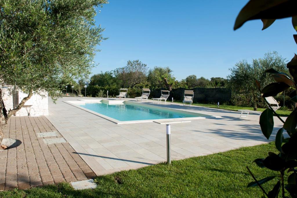 a swimming pool with chairs in a yard at Resort Pietra Bianca in Noci