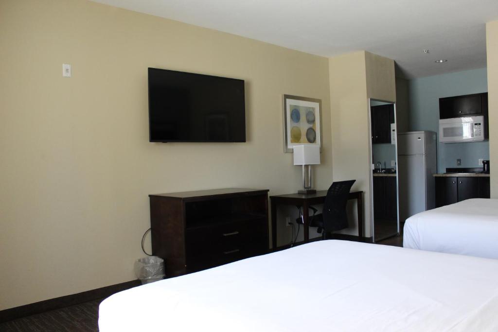 a hotel room with two beds and a flat screen tv at Horizon Inn & Suites in Pearsall