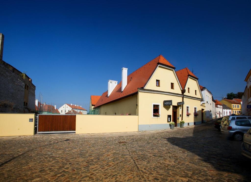 een wit gebouw met een rood dak op een straat bij Hotel Lahofer in Znojmo