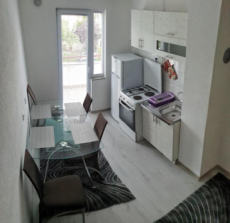 une petite cuisine avec une table en verre et une cuisinière dans l'établissement Apartment LejlaM, à Sarajevo