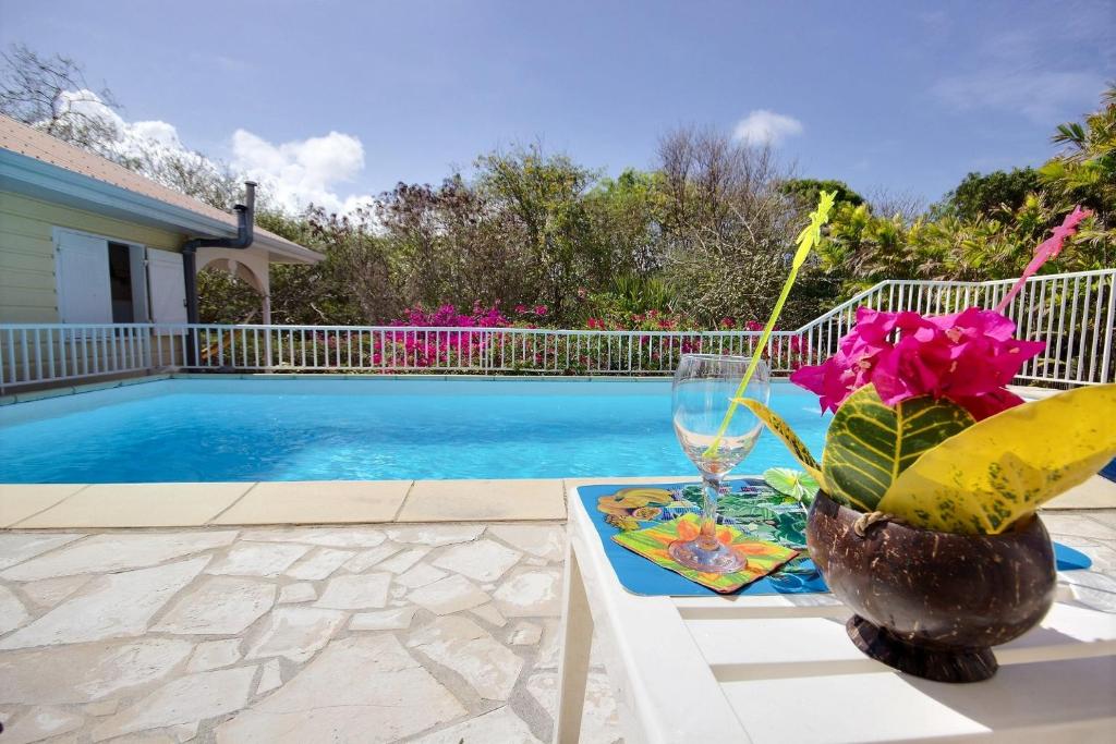 une table avec un verre de vin et un vase de fleurs dans l'établissement Villa Cattleya 4 chambres, villa avec piscine privée et grande terrasse couverte, au Vauclin