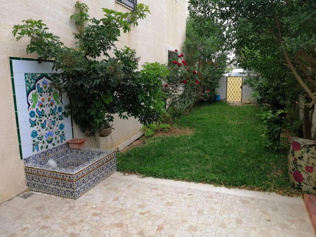 een tuin met een boom en een muur bij Maison baha in Hammamet Nord