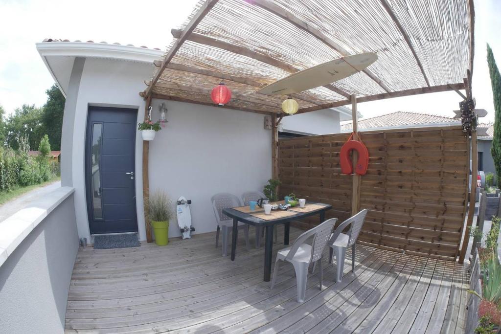 a wooden deck with a table and chairs and an umbrella at Le Porge Beach House - 4 people in Le Porge