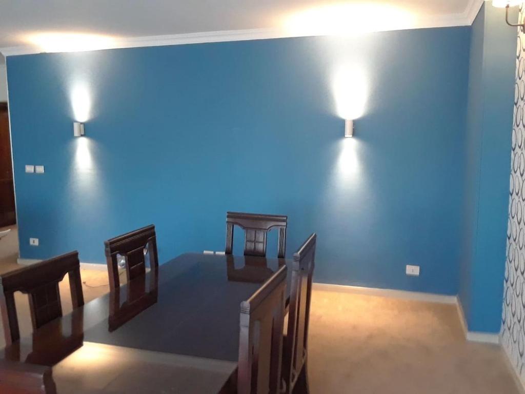 a blue wall with two tables and two lights on it at Cheerful Spacious Apartment in Rehab City , Fully Equipped, Guest First Choice & Best Offer in The City مدينة الرحاب in Cairo