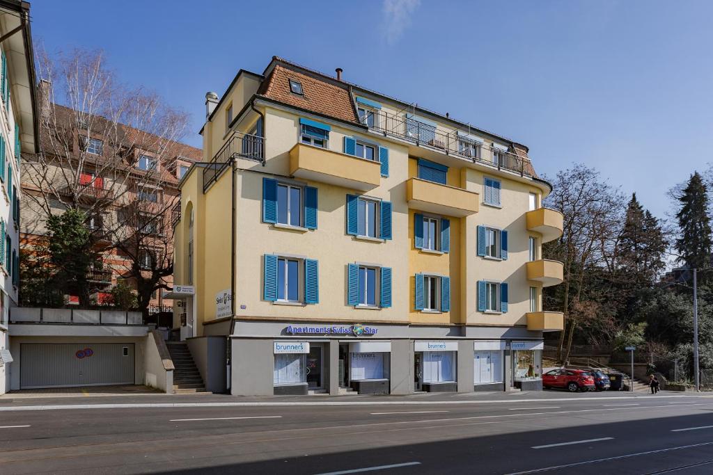 チューリッヒにあるSwiss Star Zurich University - Self Check-Inの通路上の青窓のある黄色い建物