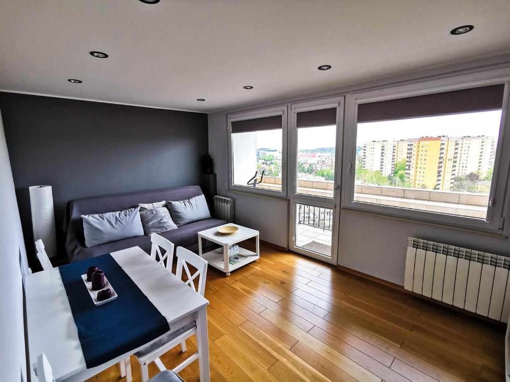 ein Wohnzimmer mit einem Sofa und einem Tisch in der Unterkunft Sky Apartments - Łagiewniki in Krakau