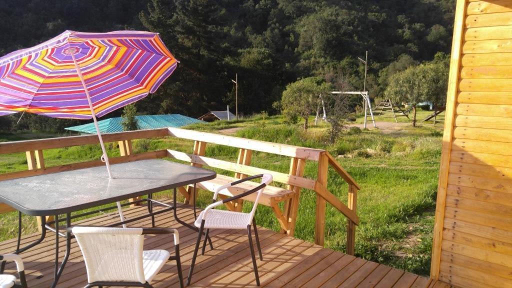 une table, des chaises et un parasol sur une terrasse dans l'établissement Refugios Olmue Santa Teresa, à El Maqui