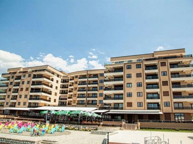 a large building with chairs and umbrellas in front of it at Park Beach Apartments in Ohrid