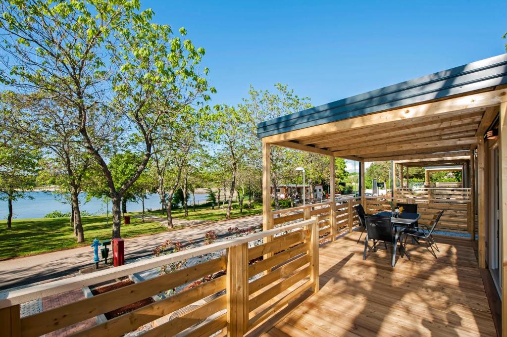 eine Holzterrasse mit einem Tisch und Stühlen darauf in der Unterkunft Eurocamp Mobile Homes at Campsite Puntica in Funtana