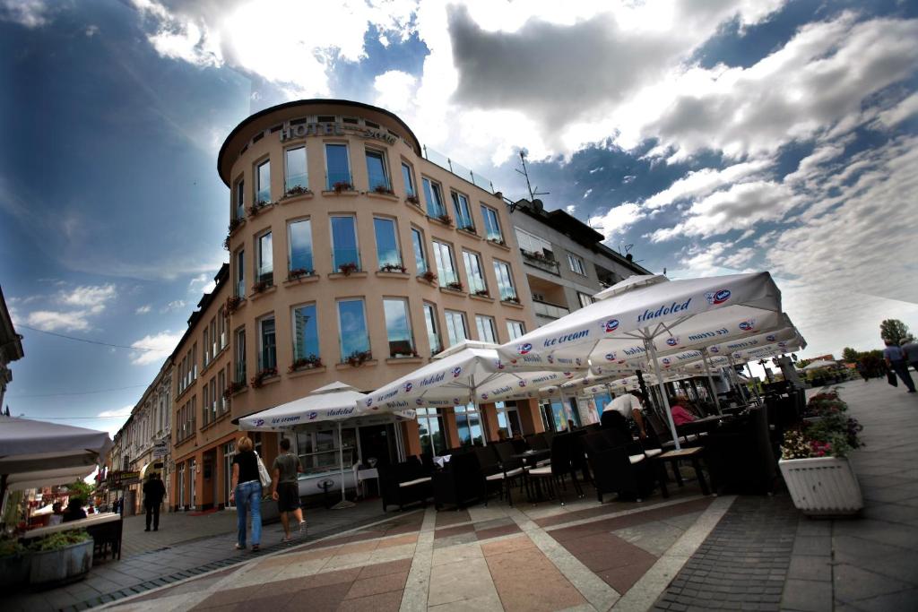 un edificio con mesas y sombrillas delante en Hotel Savus en Slavonski Brod