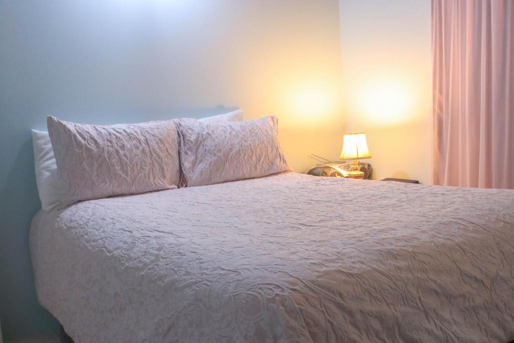 a bedroom with a bed with a white bedspread and a lamp at Chin Cozy@ Rhyne Park in Montego Bay