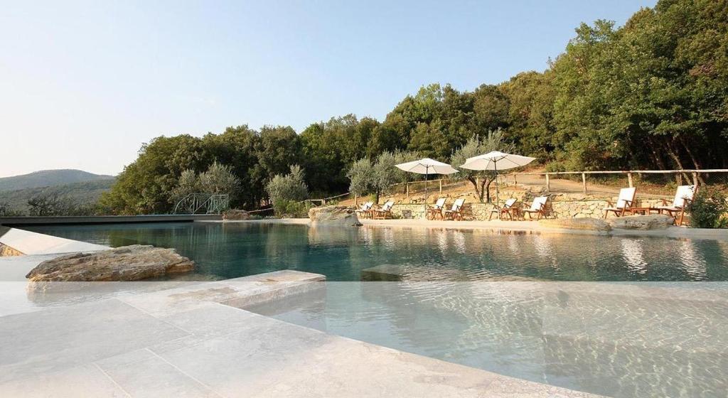 una piscina de agua con sillas y sombrillas. en Mommialla, en Gambassi Terme