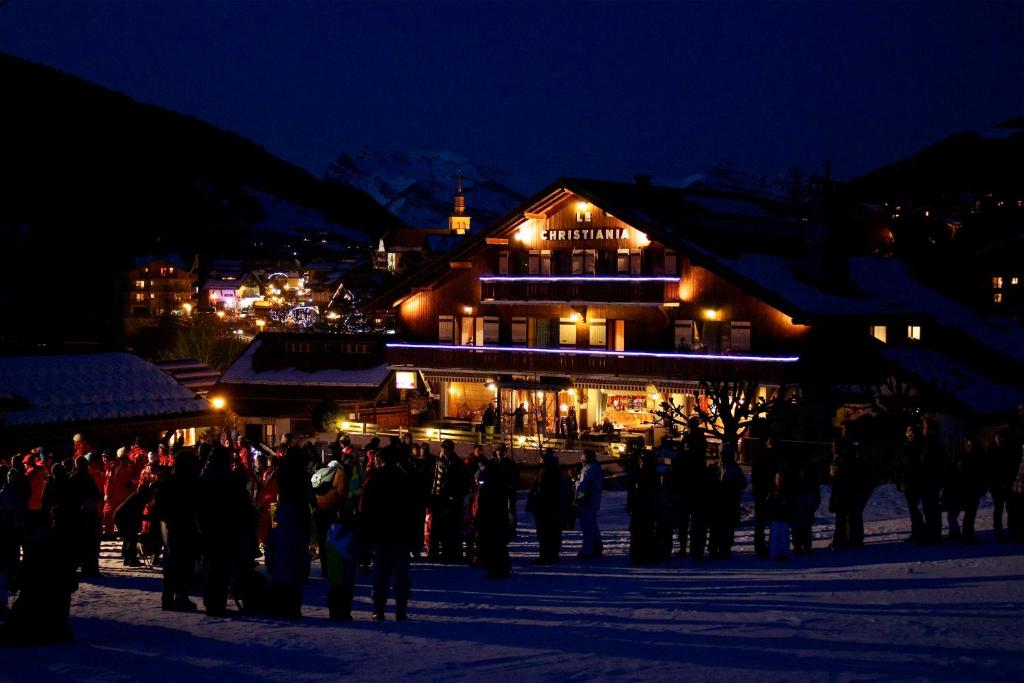 una multitud de personas de pie delante de un edificio por la noche en Hotel Le Christiania, en Les Contamines-Montjoie