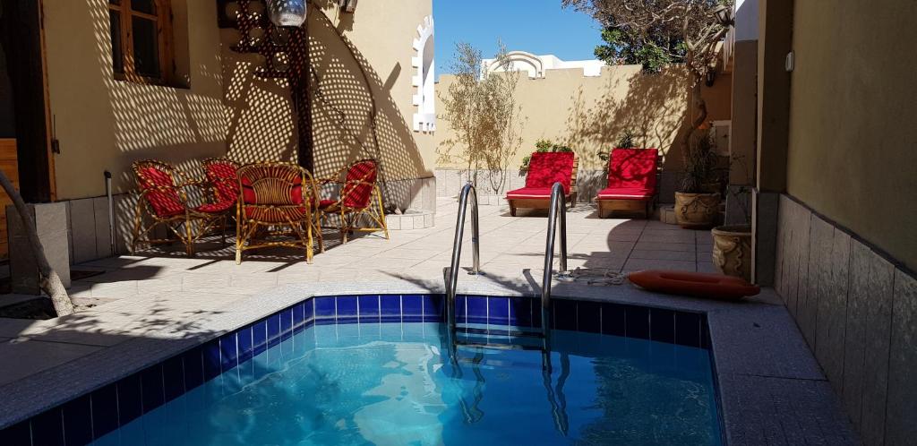 a swimming pool with red chairs and a table at Dahabcastle in Dahab