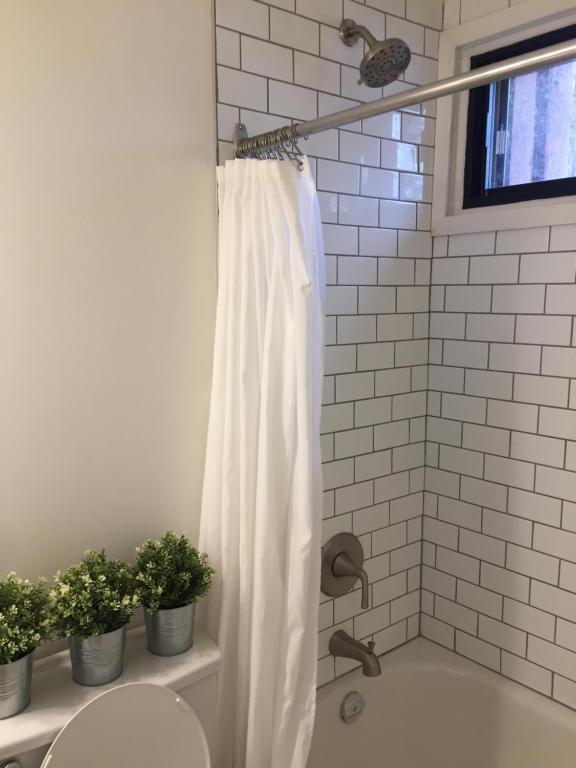 a white shower curtain in a bathroom with plants at Le Rustique Orford Domaine Cheribourg in Magog-Orford