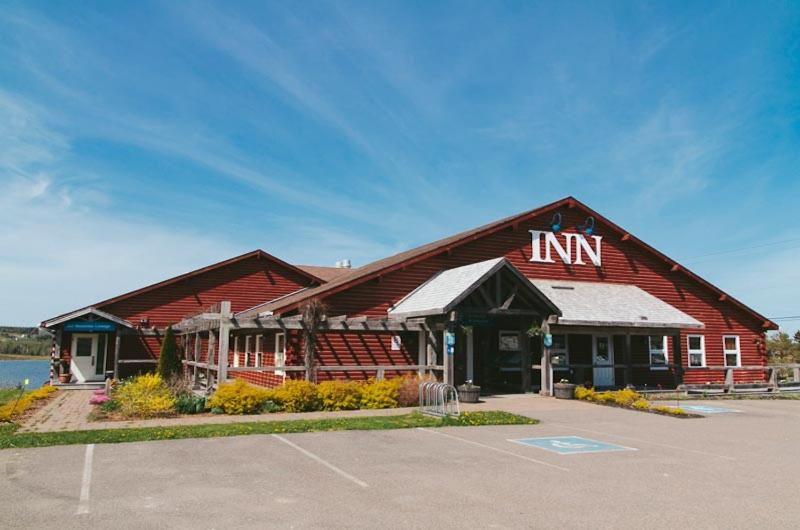 a large red building with a sign that reads inn at Bras d'Or Lakes Inn in St. Peter's