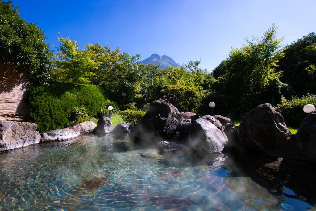 a pool of water with rocks and trees at Yufuin Sansuikan in Yufu