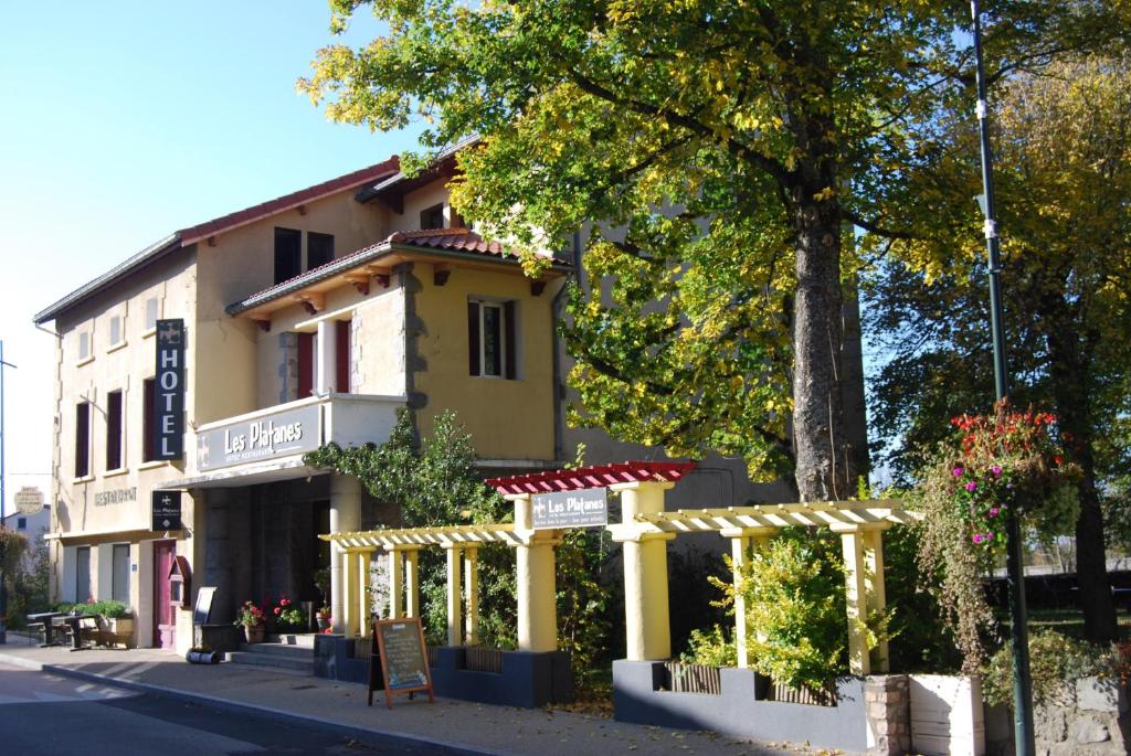 un edificio amarillo con un cartel delante en Hôtel Restaurant les Platanes, en Montfaucon-en-Velay