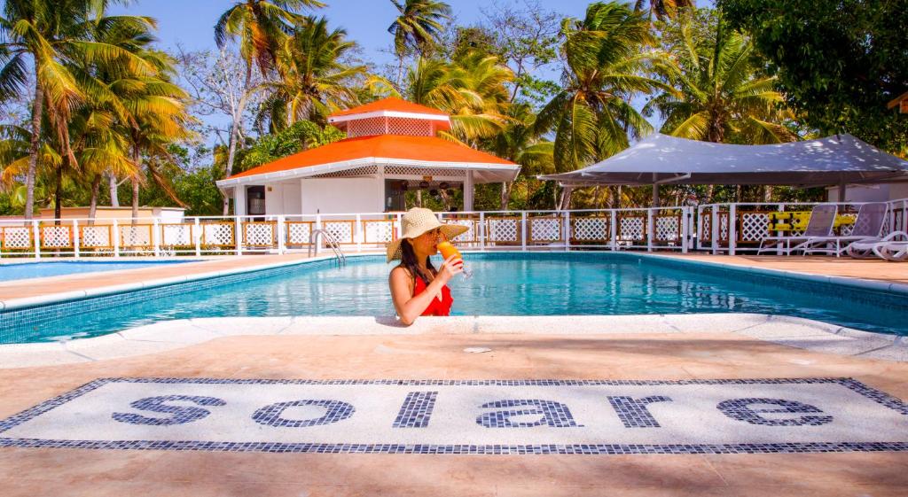a person swimming in a pool with a blue umbrella at Solare SAI Ecohotel in San Andrés