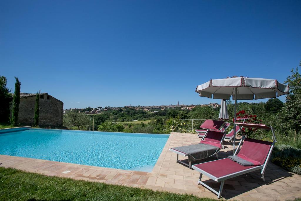zwei Stühle und ein Sonnenschirm neben einem Pool in der Unterkunft Podere La Strega in Siena