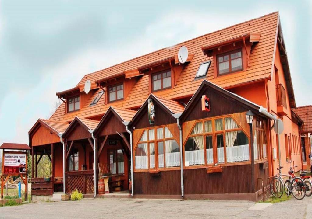 - un grand bâtiment en bois avec des fenêtres et des vélos devant dans l'établissement Határ Csárda Panzió, à Bajánsenye