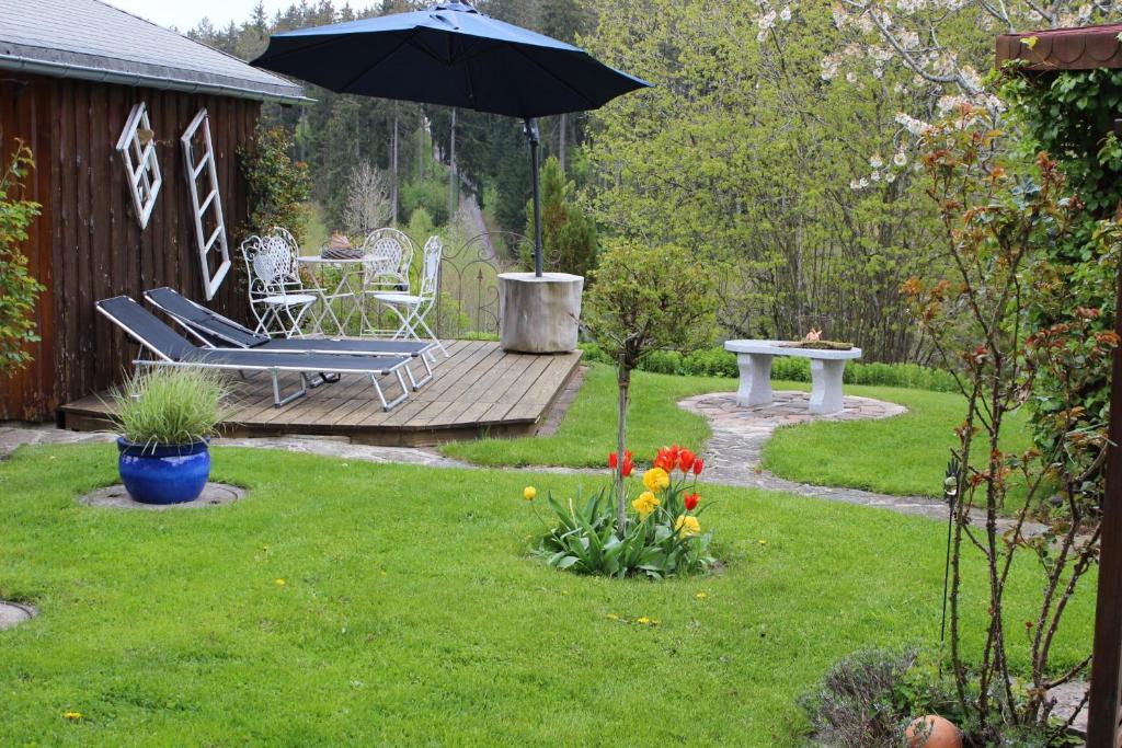 einen Garten mit einer Bank und einem Sonnenschirm in der Unterkunft Haus am Rötenberg in Grafenhausen