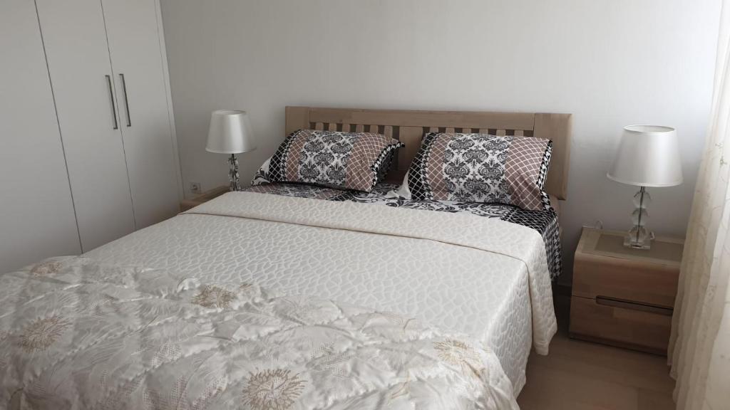 a bedroom with a bed with pillows and two lamps at Fortuna Rajna Apartman in Split