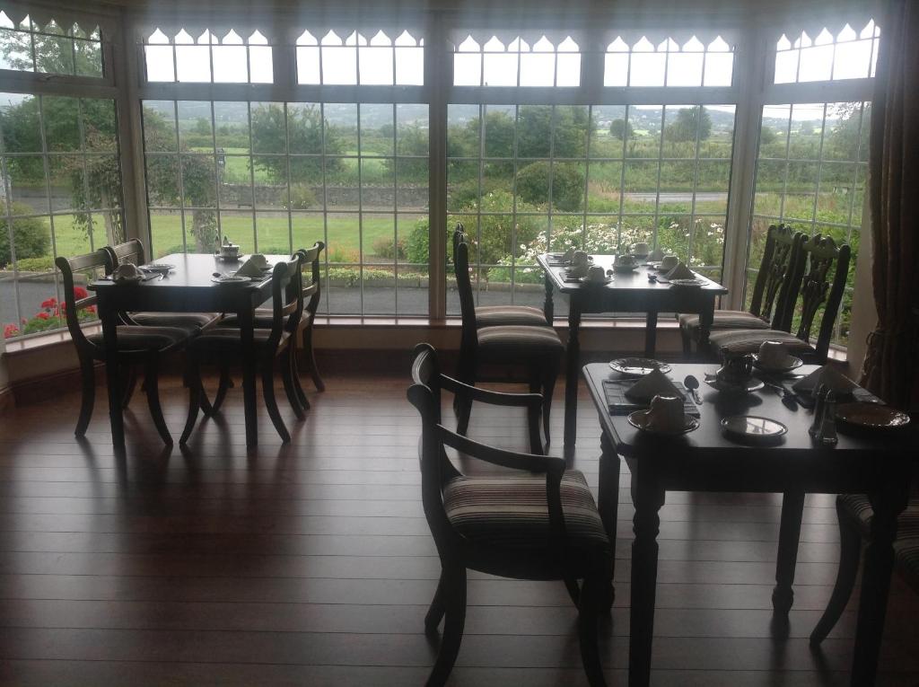 a dining room with tables and chairs and windows at Innisfree B&B in Bunratty