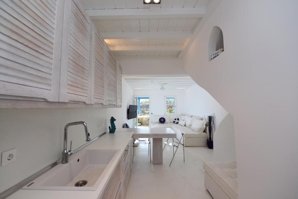 a kitchen with white counters and a sink and a table at Luxury White Maisonette in Kalafatis