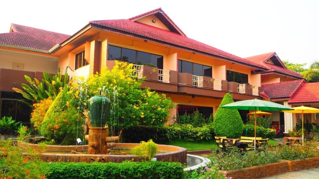 a building with a garden and a fountain in front of it at พูลวิลล่า เชียงใหม่ in Doi Saket