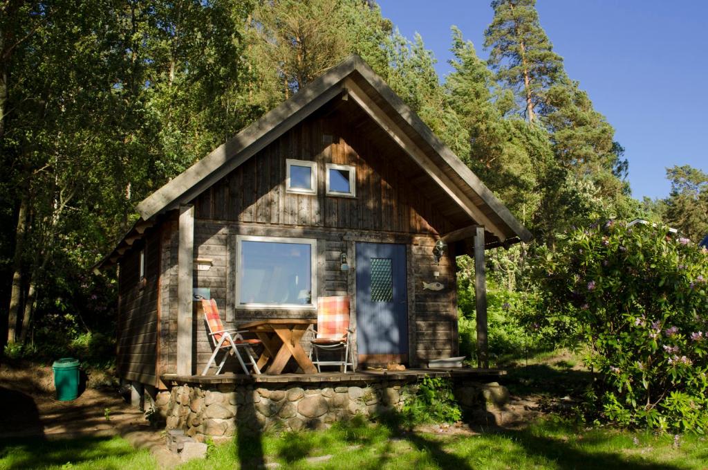 een hut in het bos met een tafel en twee stoelen bij Strandstuga in Tämta