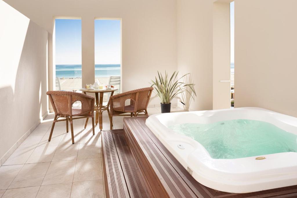 una vasca da bagno in una stanza con tavolo e sedie di Hotel Ambassador a Rimini