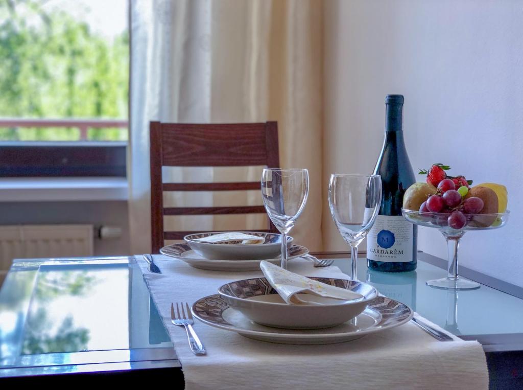 a table with plates and glasses and a bottle of wine at Apartamenty Łagiewniki in Krakow