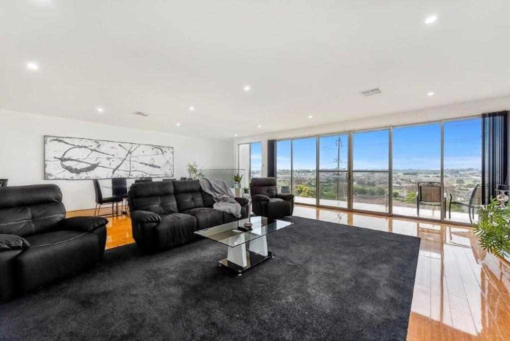 a living room with black furniture and large windows at BENGALEE EXECUTIVE TOWNHOUSE- MODERN & STYLISH in Mount Gambier