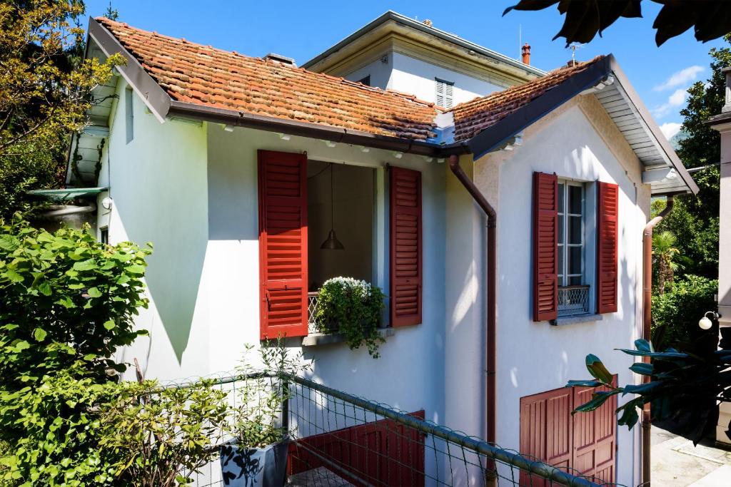 a small white house with red shutters at Little Garden House in Cernobbio