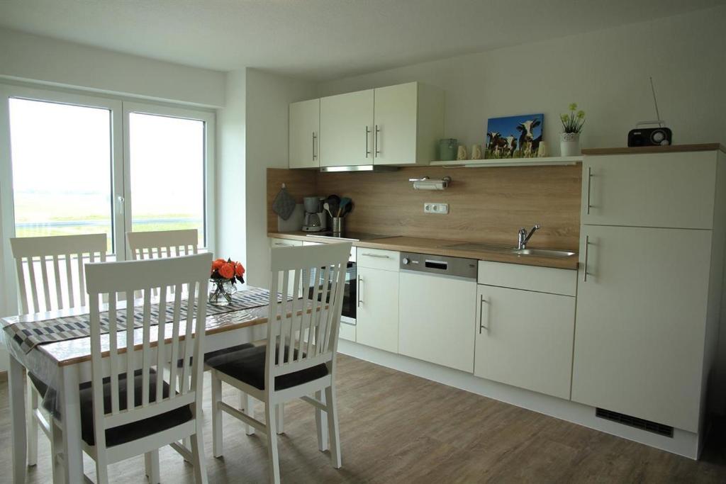 a kitchen with white cabinets and a table and chairs at Haus am Meer in Vollerwiek