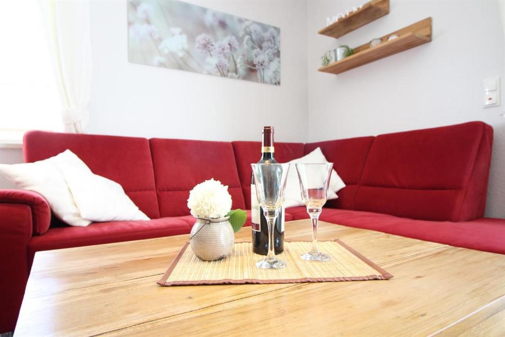 a living room with a red couch and a table with wine glasses at Diekje Deel in Sankt Peter-Ording