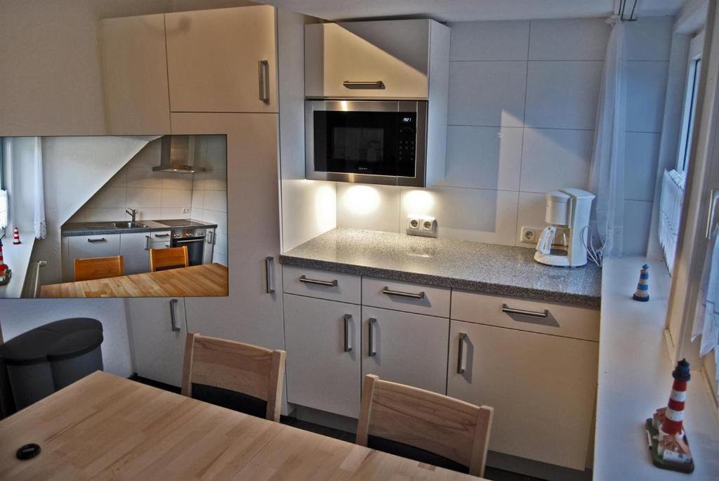 une cuisine avec des placards blancs et une table avec des chaises dans l'établissement Haus Abendsonne, à Sankt Peter-Ording