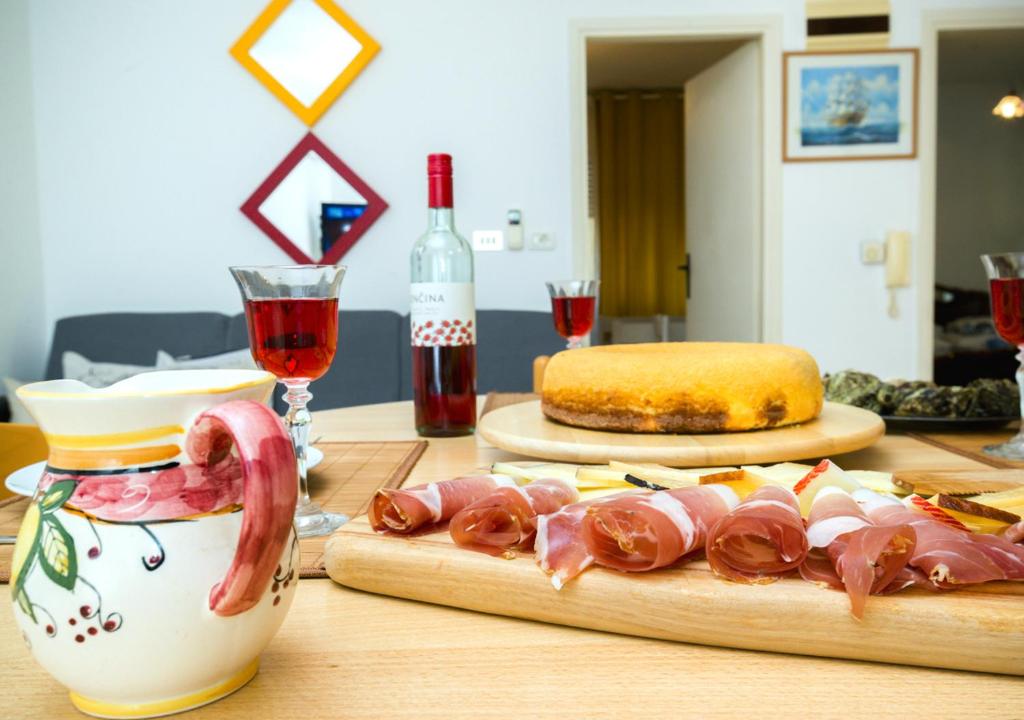 a table with meat and a bottle of wine and glasses at Apartment Dora in Umag