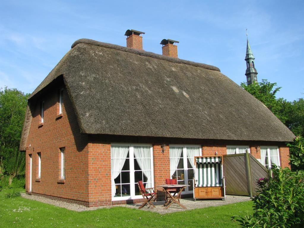 a large brick house with a thatched roof at Haushälfte Luv und Lee in Tating