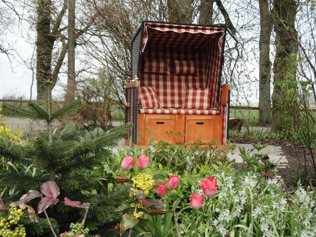 a chair sitting in the middle of a garden with flowers at Der Mithinghof in Kotzenbüll