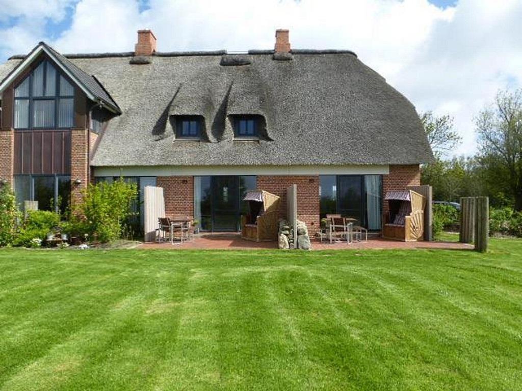 una casa grande con césped delante en Ferienwohnung unter Reet, en Westerhever