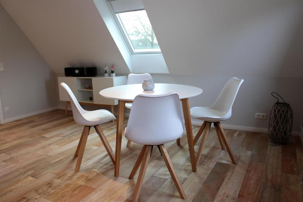 a table and four white chairs in a room at Ferienhaus Wiedingharde II in Tating