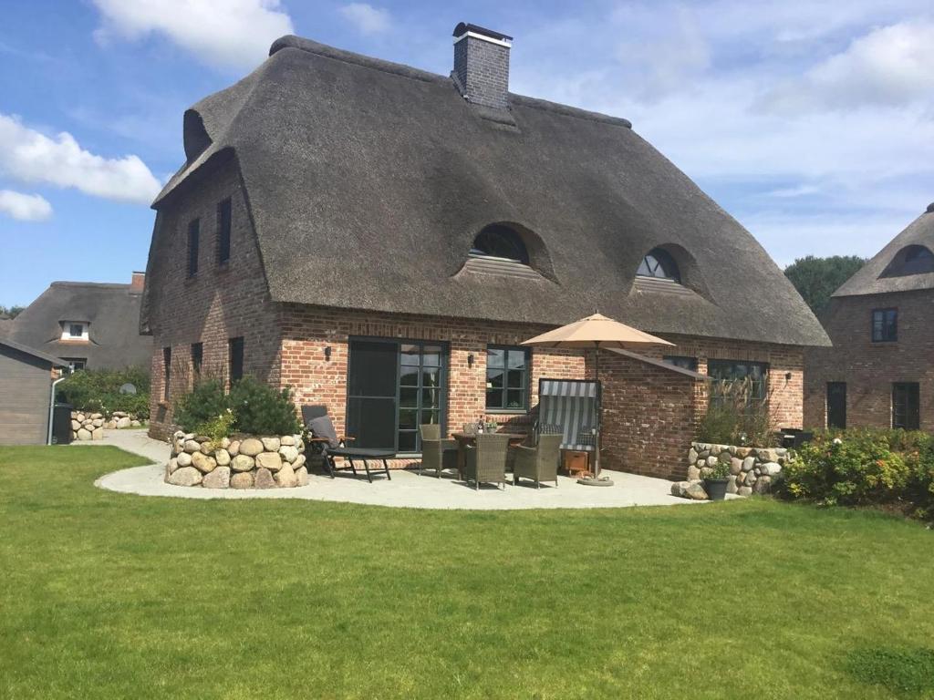 a large brick house with a thatched roof at Ferienhaus Auszeit in Tating