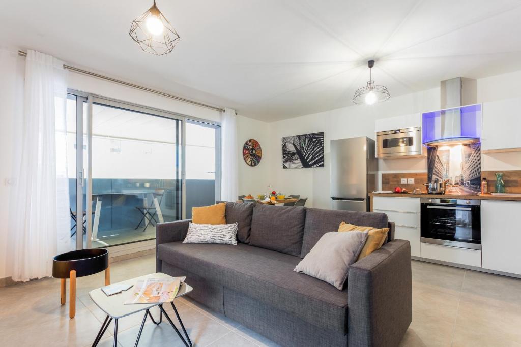 un salon avec un canapé et une cuisine dans l'établissement Luminescence Parc Marianne - Première conciergerie, à Montpellier