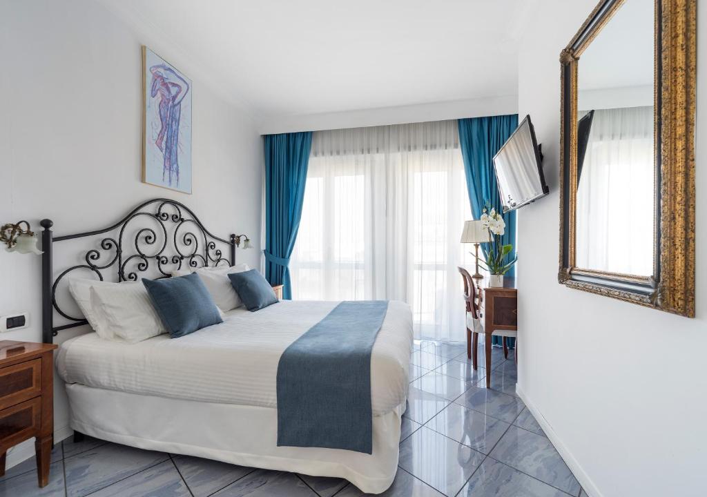 Fiorentini Residence NAPOLI في نابولي: غرفة نوم بسرير كبير مع ستائر زرقاء ومرآة