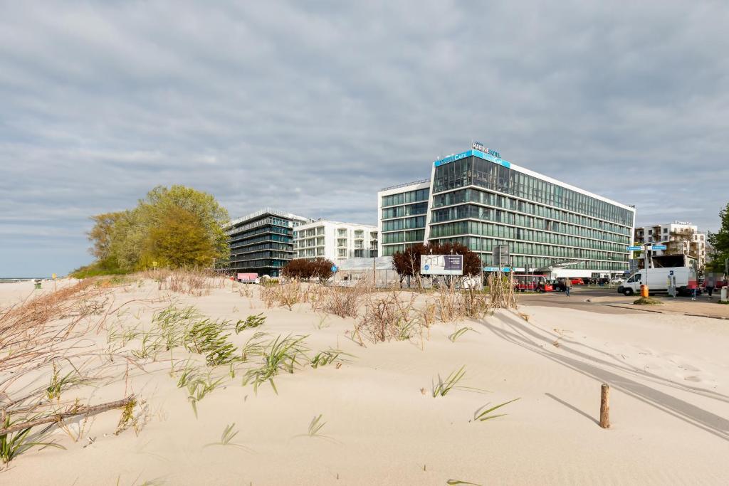 a building on the beach next to a sandy beach at Apartamenty Olympic Park by Renters in Kołobrzeg