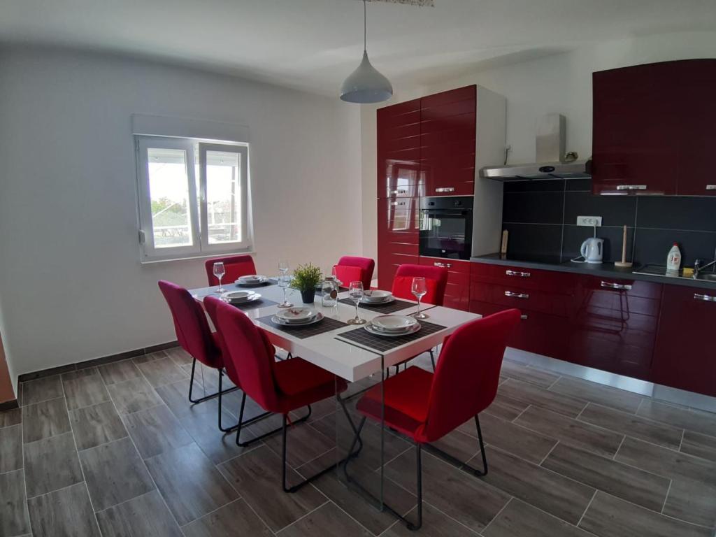 Donji Zemunik的住宿－Holiday House Ivan，一间带桌子和红色椅子的用餐室